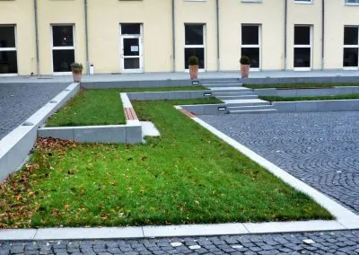 Betonfertigteile fassen Rasenflächen ein und trennen den Natursteinpflasterbelag