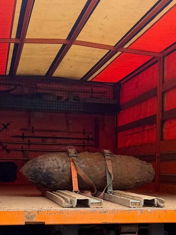 Eine verrostete Fliegerbombe liegt auf Unterlegschienen im orangefarbenen Kastenwagen des Kampfmittelbeseitigungsdienstes, mit zwei Spanngurten gesichert.