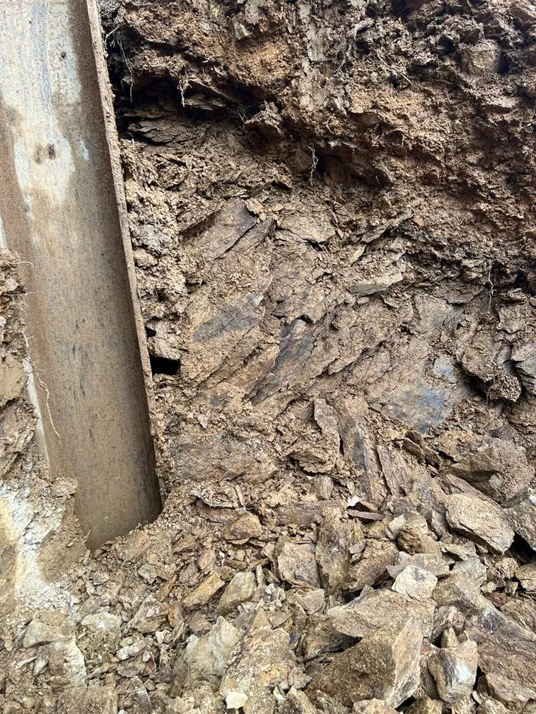Ein Stahlträger HEB 400 steckt in plattigem Ton- und Sandstein, daneben die freigelegte Felswand