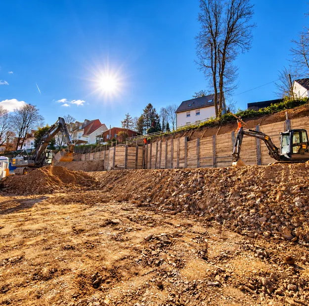Kettenbagger der PILOT GmbH beim Aushub der Baugrube in Remscheid vor der Stützmauer des Nachbargrundstücks
