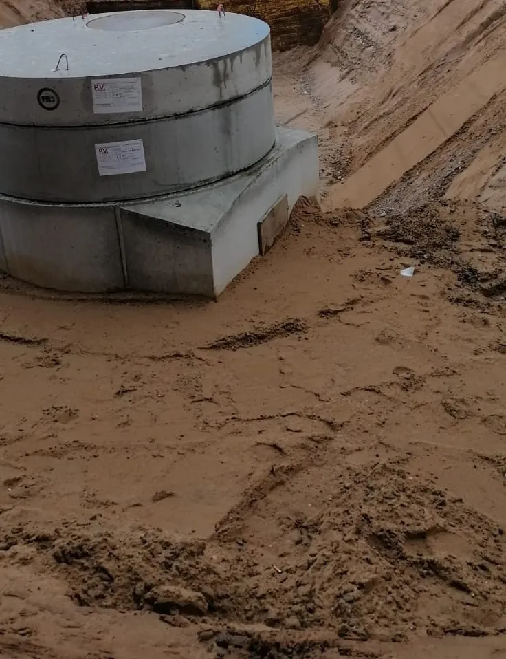 Betonschacht DN 1000 in einer geböschten Baugrube mit Verbauplatten an einem Bürogebäude